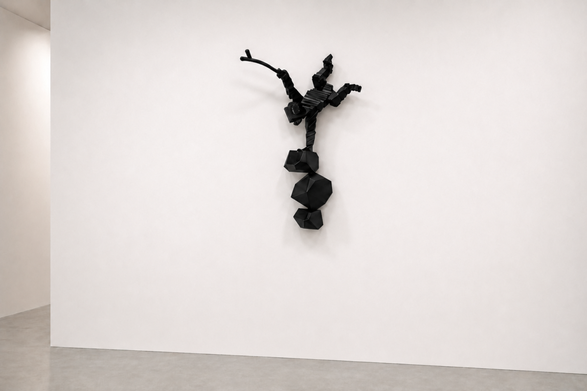 Abstract black geometric sculpture mounted on a white gallery wall, resembling a humanoid figure with angular shapes.